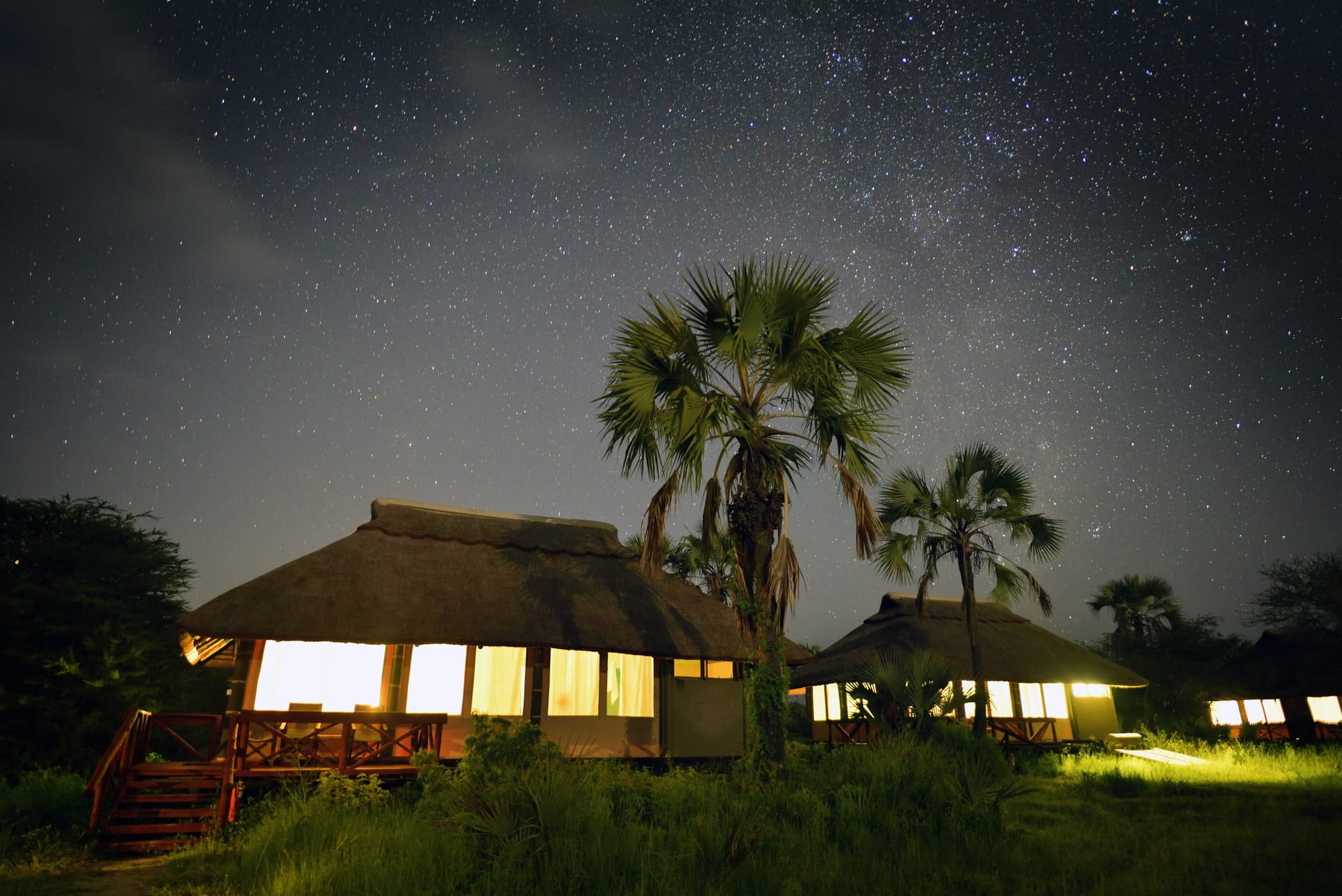 Thatched lodge bandas lit from within beneath a sky full of stars